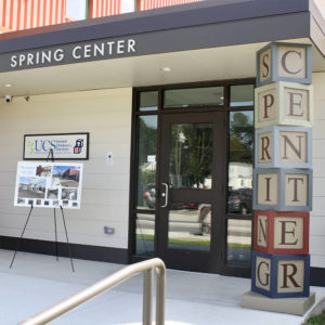 The entrance to the new Spring Center. The overhang above the front door says "Spring Center" The support holding the overhang is made up of larger than life letter block toys that spell out "Spring Center"