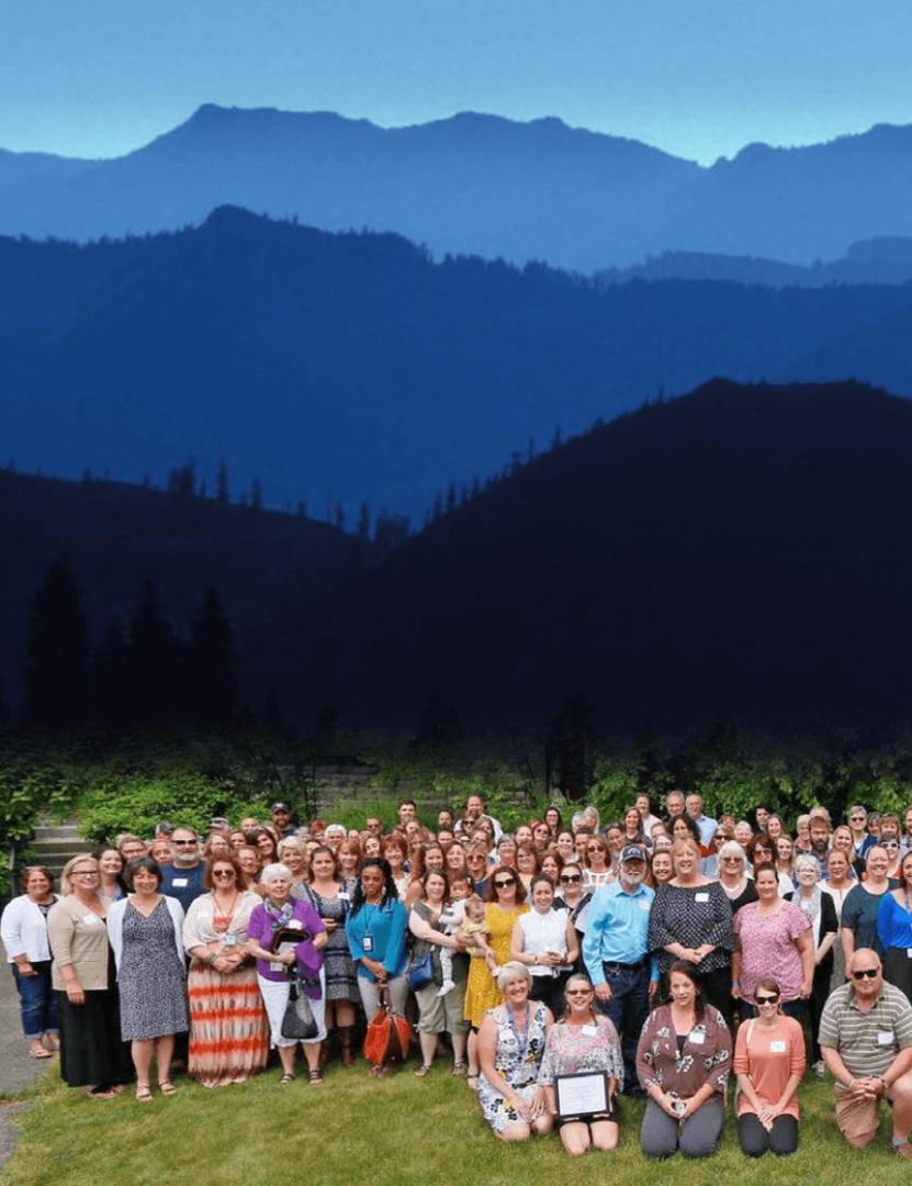 A group photo of all UCS staff that boends into a painting of a mountain range above with the UCS logo and the text "Annual Report 2017-18"