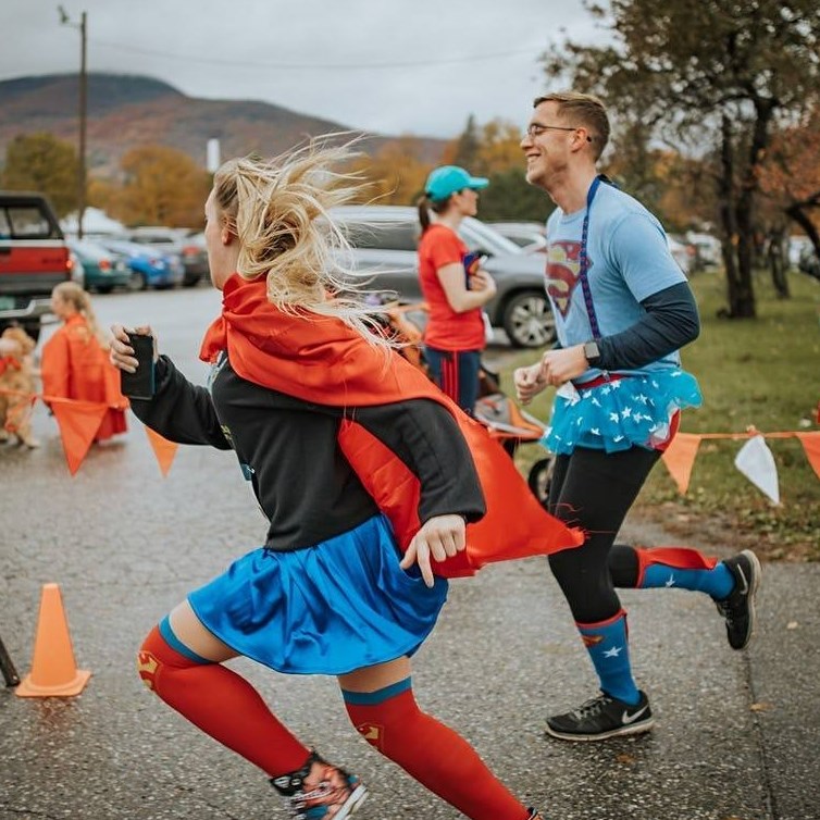 A woman and man dressed as superheros running in a race