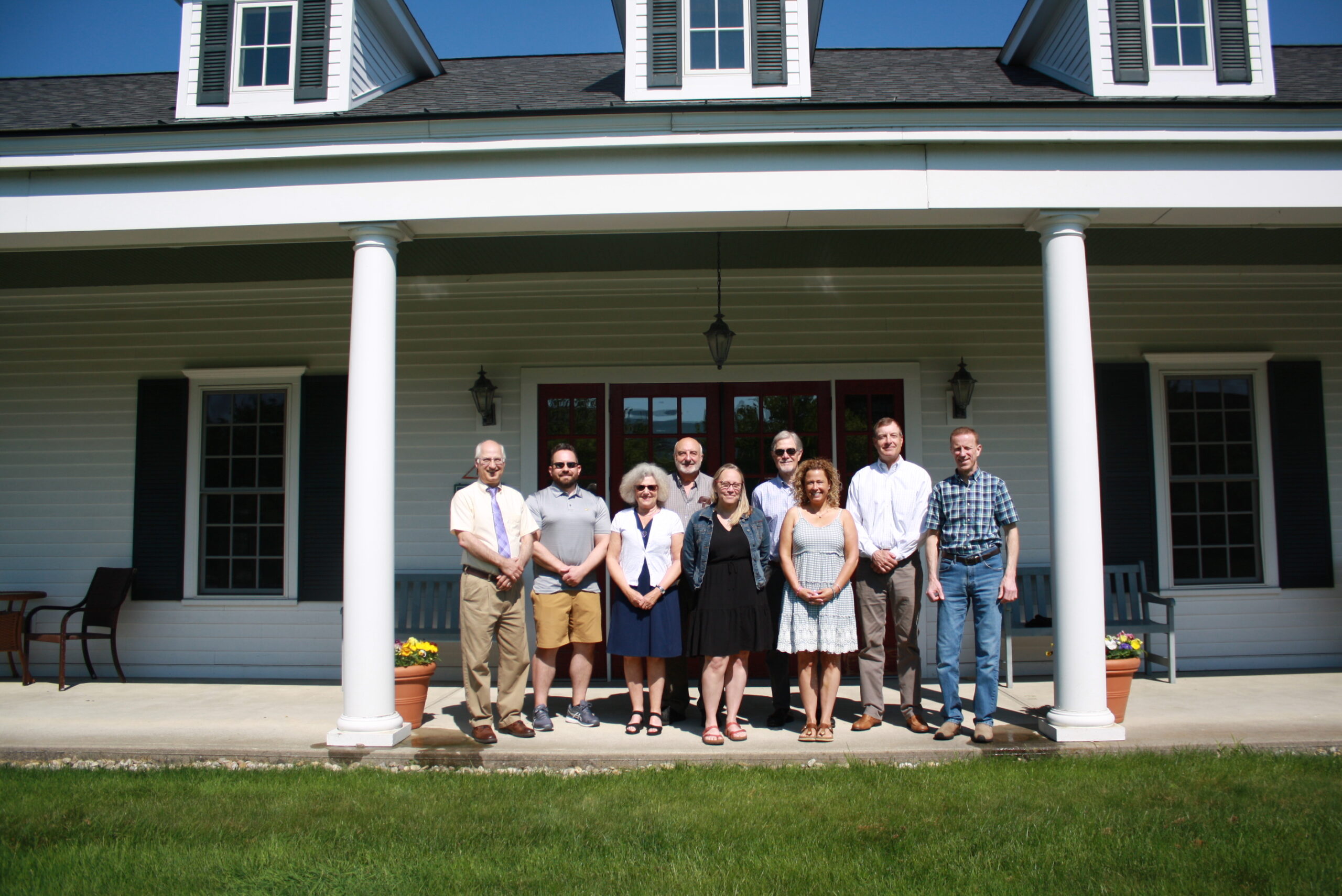 group of people smiling in front of a historic white building with pillars