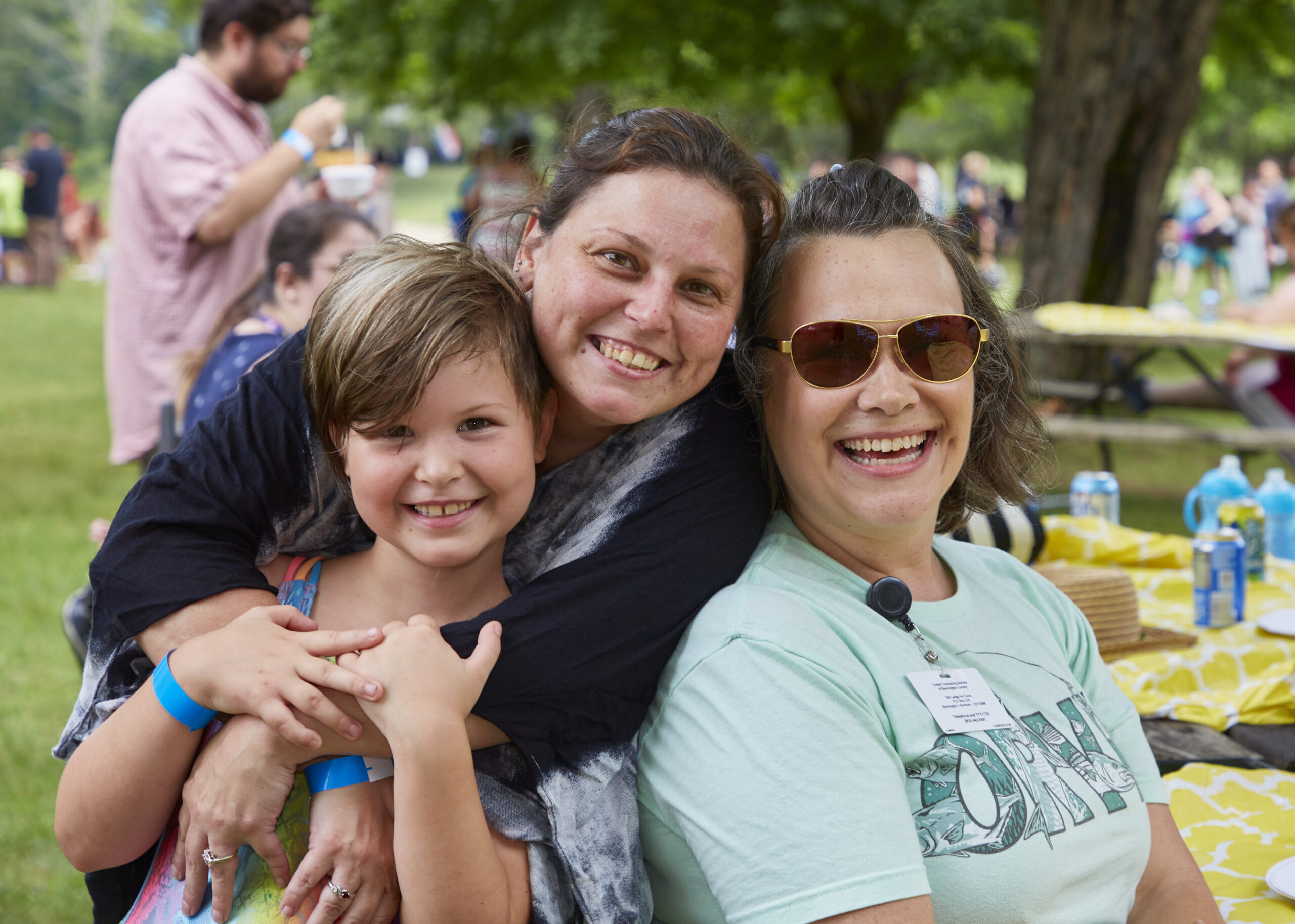 a child and woman are hugging and smiling with another woman